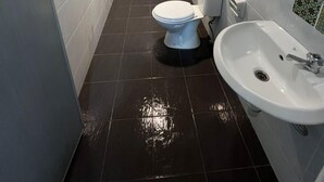 Une petite salle de bain moderne, avec des carreaux blancs, des toilettes, un bidet et un lavabo.