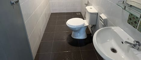 A small, modern bathroom with white tiles, a toilet, a bidet, and a sink.