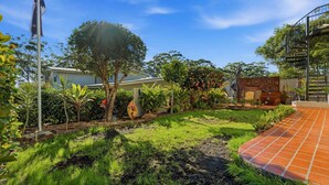 A residential garden with a patio, a staircase, and a variety of plants.