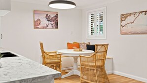 A dining area with a round table, wicker chairs, and a white ceiling light.