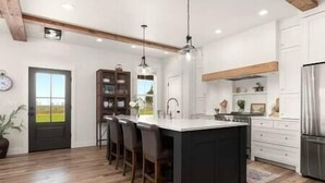 A modern kitchen with a central island, wooden flooring, and pendant lighting. - Luxe Barndominium - Mtn Views! "Hemlock" (Columbia Falls)