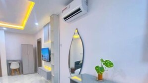 A modern bedroom with a vanity, a mirror, an air conditioning unit, and a small plant. - Studio(S7) @ LEKKI PHASE 1. 24/7 AC. By NgoZiLiving


 (Lekki, phase 1)