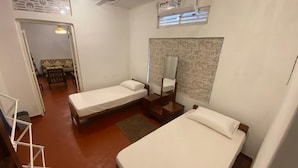 A compact hotel room with two single beds, a small sitting area with a sofa and table, a mirror, and a ceiling fan. - AC Home in Wellawatta Colombo 06 - 2AC Bedrooms & Servant/Guest room (Colombo)