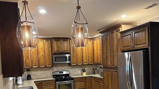A modern kitchen with wooden cabinets, stainless steel appliances, and a granite countertop. - Cajun Country Escape  (Gonzales)