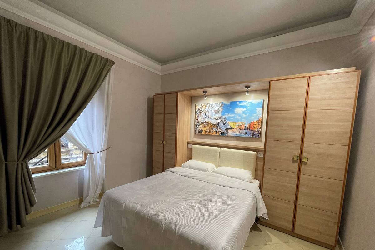 A bedroom with a bed, a wardrobe, and a painting on the wall.