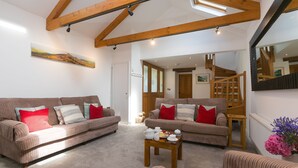 Ein Wohnzimmer mit zwei braunen Sofas, einem Holztisch und einer Treppe, die in einen anderen Raum führt.