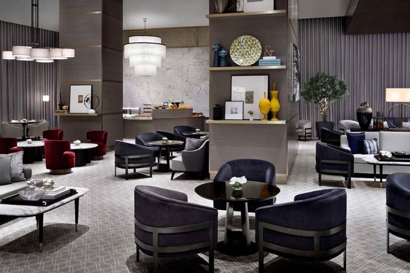 Een moderne hotelentree met zithoeken, een receptiebalie en decoratieve elementen zoals een kroonluchter en kunstwerken.