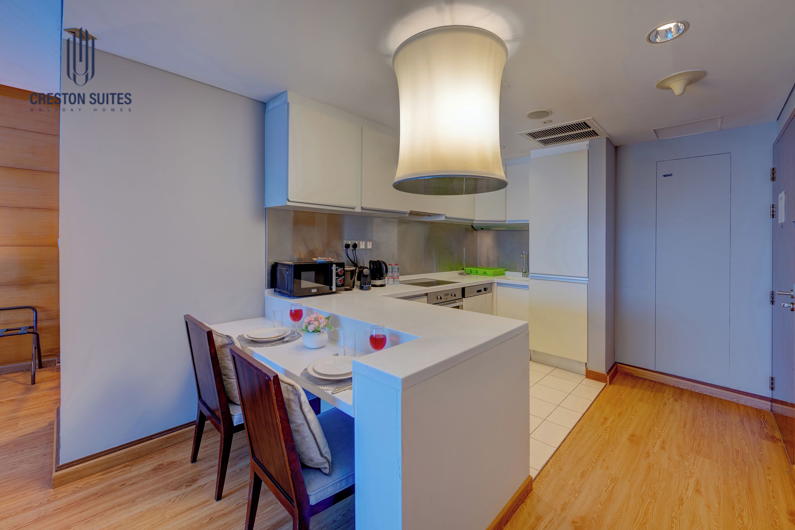 A modern kitchen with white cabinetry, a central island with seating, and a hanging light fixture.