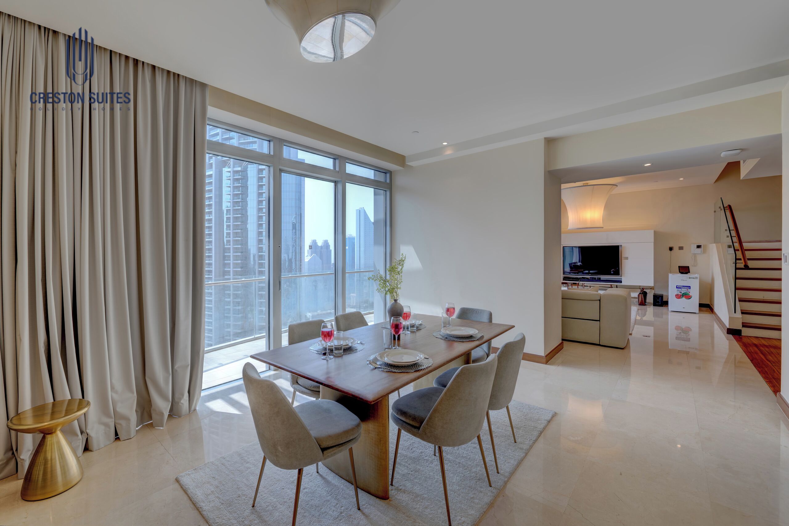 A modern dining area with a large table, chairs, and a view of the city through large windows.