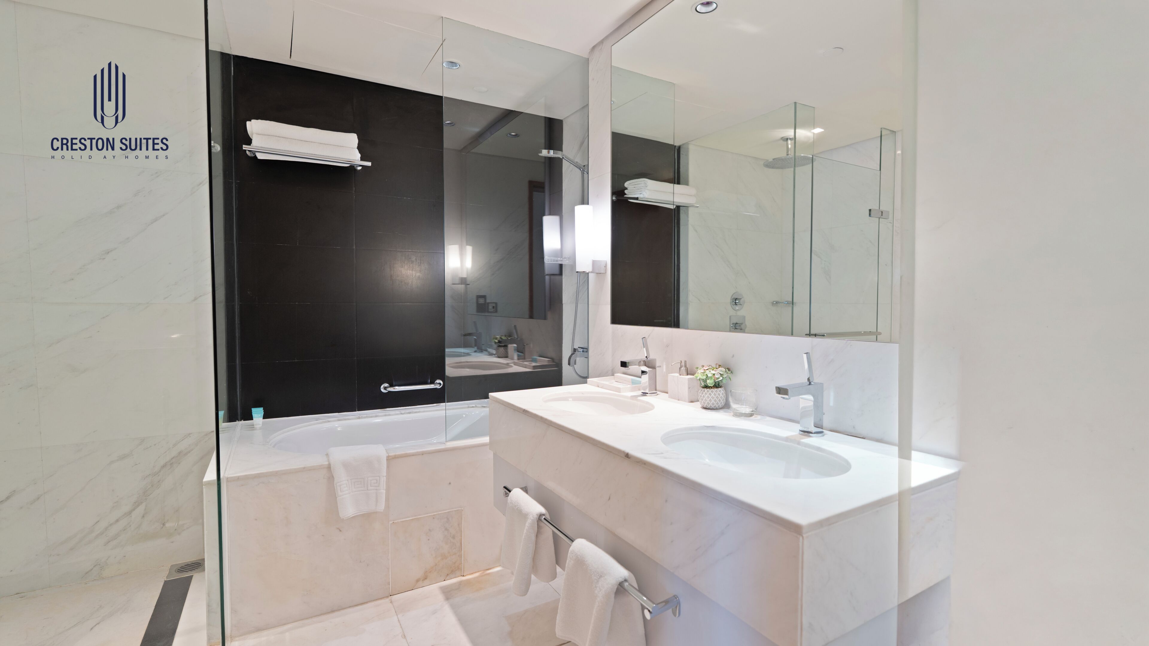 A modern bathroom with a glass shower enclosure, a large mirror, and a white vanity with two sinks.