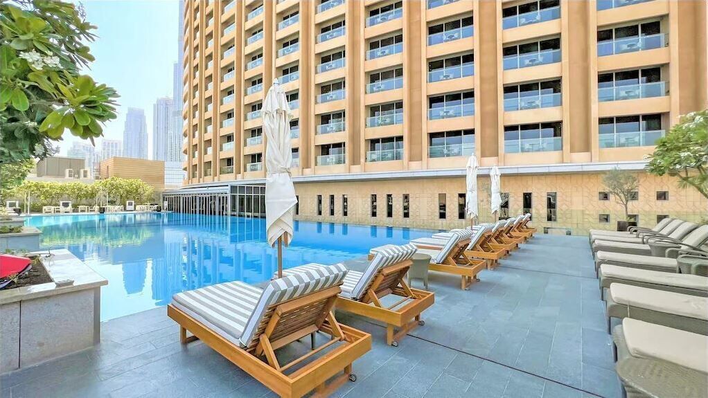 Un espace piscine aménagé sur le toit, avec des chaises longues et une vue sur un immeuble de grande hauteur.