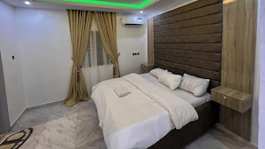 A modern bedroom with a bed, curtains, and a wooden headboard. - The Neat Place  (Kaduna)