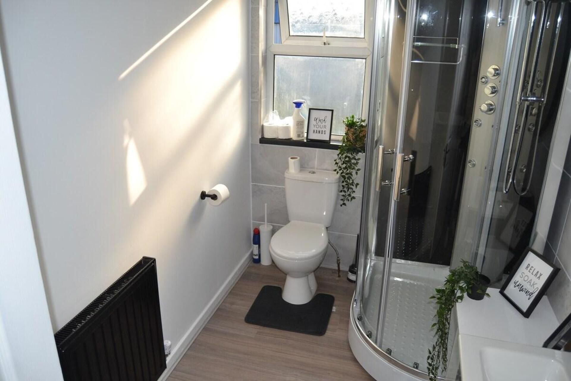 A modern bathroom with a toilet, shower, and a small window.