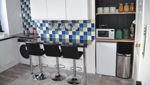 A compact kitchen with a checkered backsplash, a microwave, a small refrigerator, and a trash bin. - Modern Home Close to City Centre (Leeds)