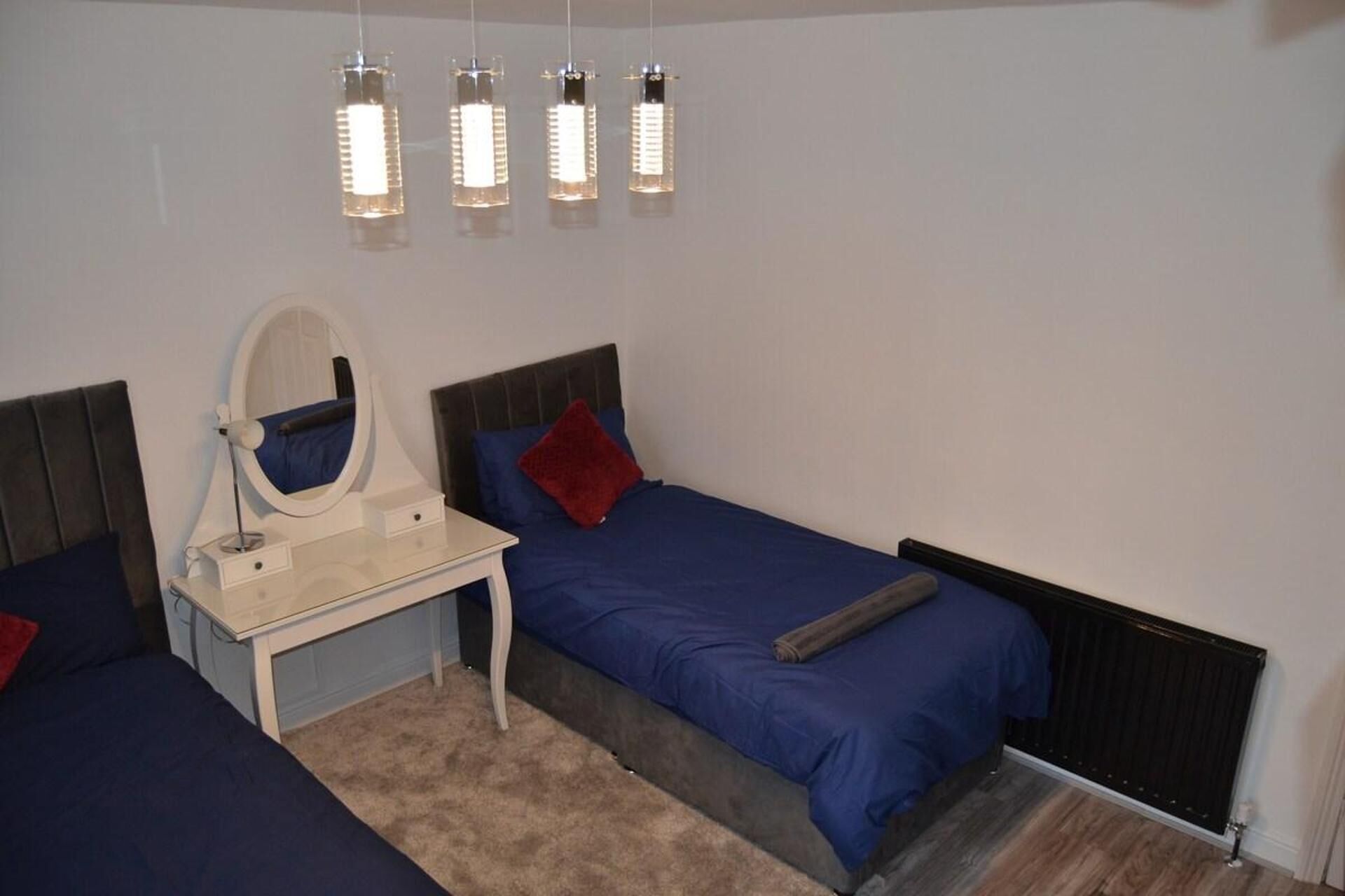 Une chambre avec deux lits, une table de chevet avec un miroir et une commode.