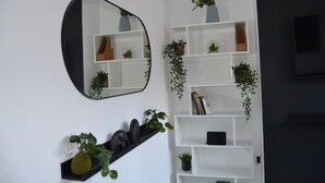A modern living room with a large mirror, white shelving units, and various potted plants. - Modern Home Close to City Centre (Leeds)