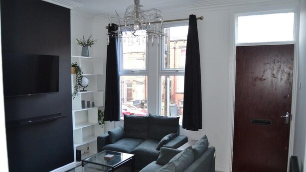 A living room with a sofa, a coffee table, a TV, and a bookshelf. - Modern Home Close to City Centre (Leeds)