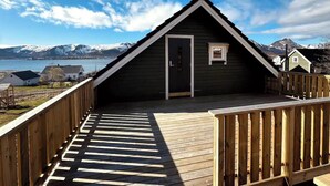 Una terraza de madera con vista a una montaña y un lago.