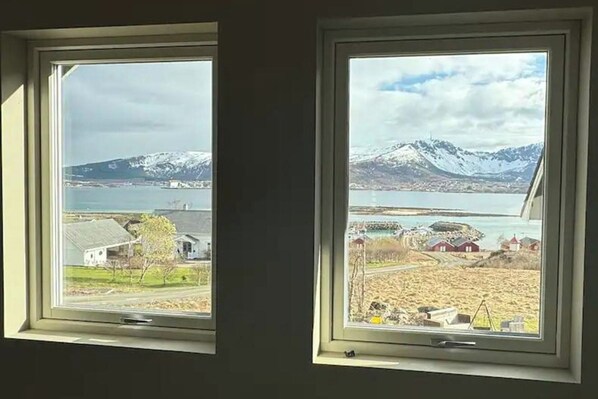 Two windows with views of a lake, mountains, and a small village. - 1 Bed Loft Sleeps 4 -hot Tub, Sauna & Pets Ok (Hadsel)