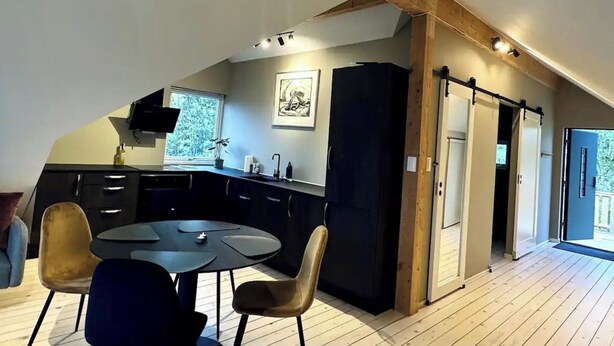 Una cocina moderna con comedor, piso de madera y un ventanal grande.