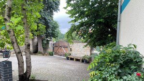A paved courtyard with a stone wall, a wooden gate, and potted plants. - Apartment in HOFGOHLIS between Dresden, Meißen and Radebeul directly on the Elbe cycle path (Dresden)