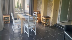 A dining area with a wooden table and white chairs, a small wooden stool, and a stone wall. - Apartment in HOFGOHLIS between Dresden, Meißen and Radebeul directly on the Elbe cycle path (Dresden)