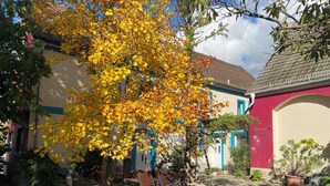 A courtyard with a tiled floor, a bench, and a tree with yellow leaves. - Apartment in HOFGOHLIS between Dresden, Meißen and Radebeul directly on the Elbe cycle path (Dresden)