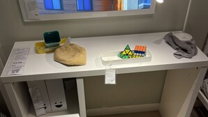 Un bureau blanc avec un écran d’ordinateur, une lampe de bureau, un plateau de jeu de puzzle, une trousse à crayons et une boîte de mouchoirs.