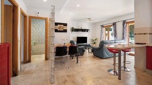 Una sala moderna con sofá, televisión y un comedor con sillas.