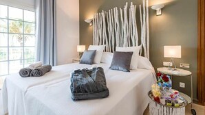 Camera d'albergo con un letto grande, due comodini con lampade, una lampada a parete e una finestra con tende.