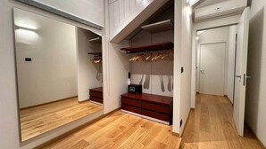 Un vestidor amplio con suelo de madera, estanterías empotradas y una puerta de armario con espejo.