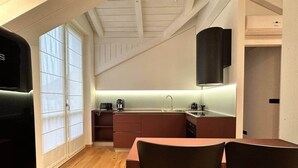Una cocina compacta con comedor, suelo de madera y techo alto con vigas a la vista.