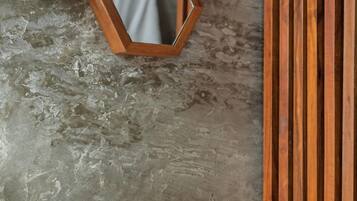 A spa area with wooden slats, a hexagonal mirror, and a white towel on a wooden bench.