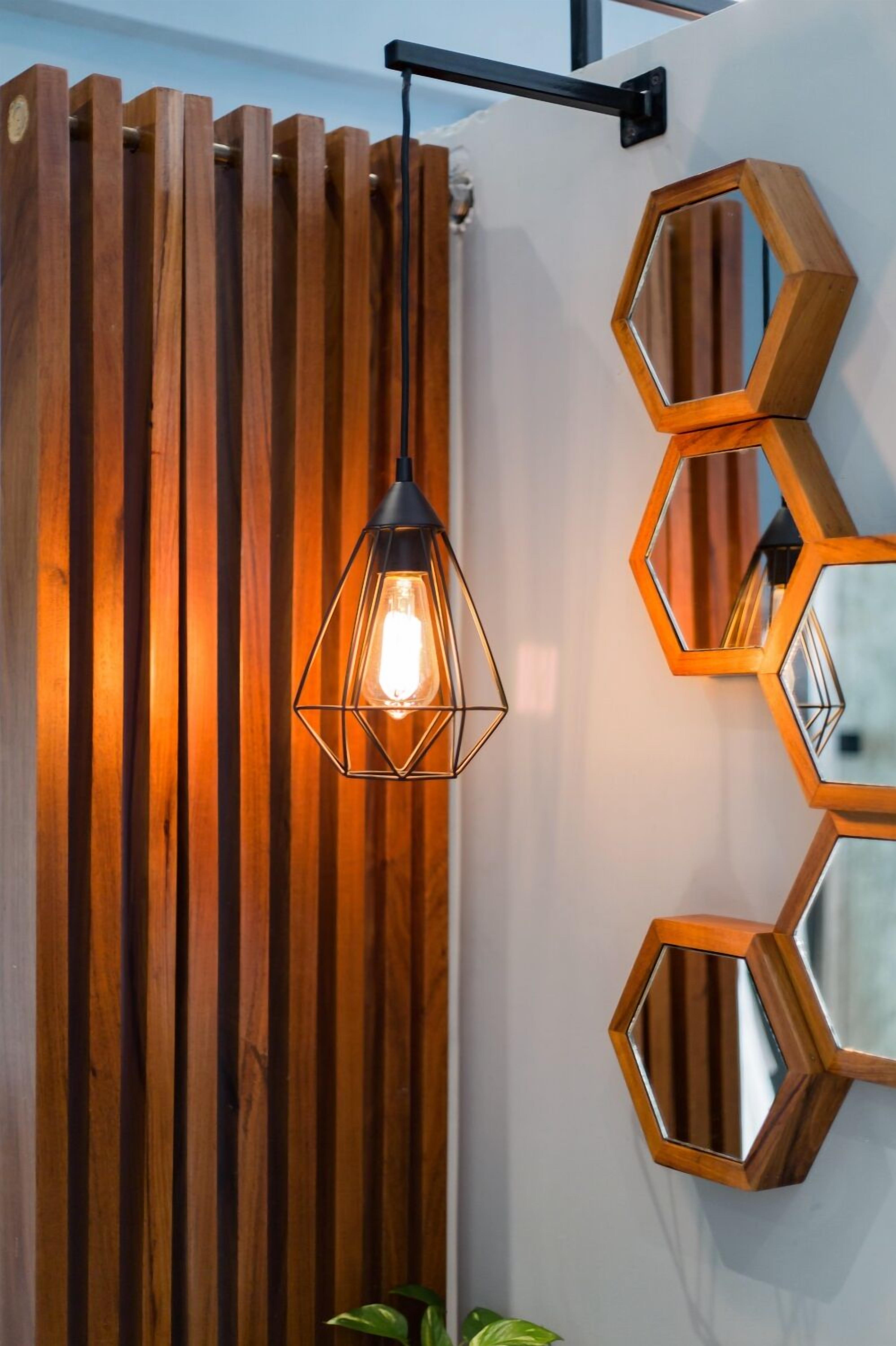 A wooden slat wall with a hanging light fixture and hexagonal mirrors.