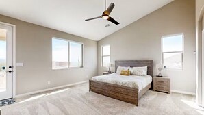 Un dormitorio amplio con una cama grande, un ventilador de techo y dos mesitas de noche.