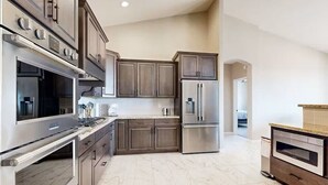 Una cocina moderna con electrodomésticos de acero inoxidable, armarios de madera y suelo de mármol.