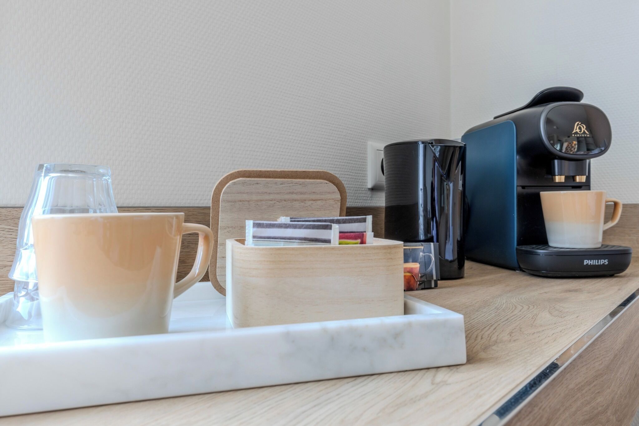 A coffee station with a coffee maker, two cups, a tray, and a card holder.
