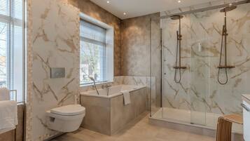 A modern bathroom with a freestanding bathtub, a glass-enclosed shower, and a toilet.