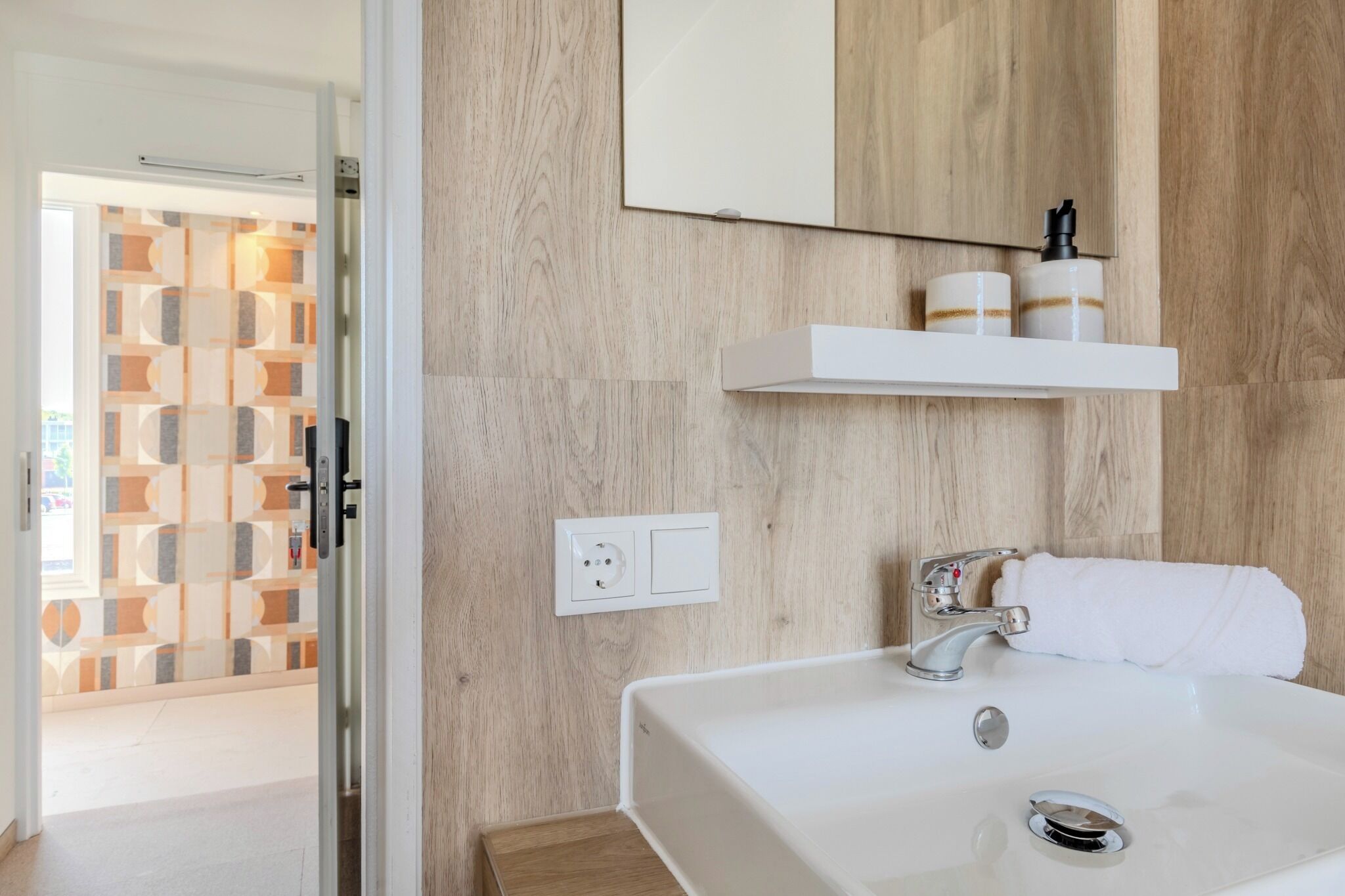 A modern bathroom with a white sink, a mirror, and a towel.