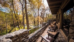 A stone-walled balcony with wooden chairs and a table, overlooking a forested area with autumn foliage. - Briar Patch Inn (Sedona)