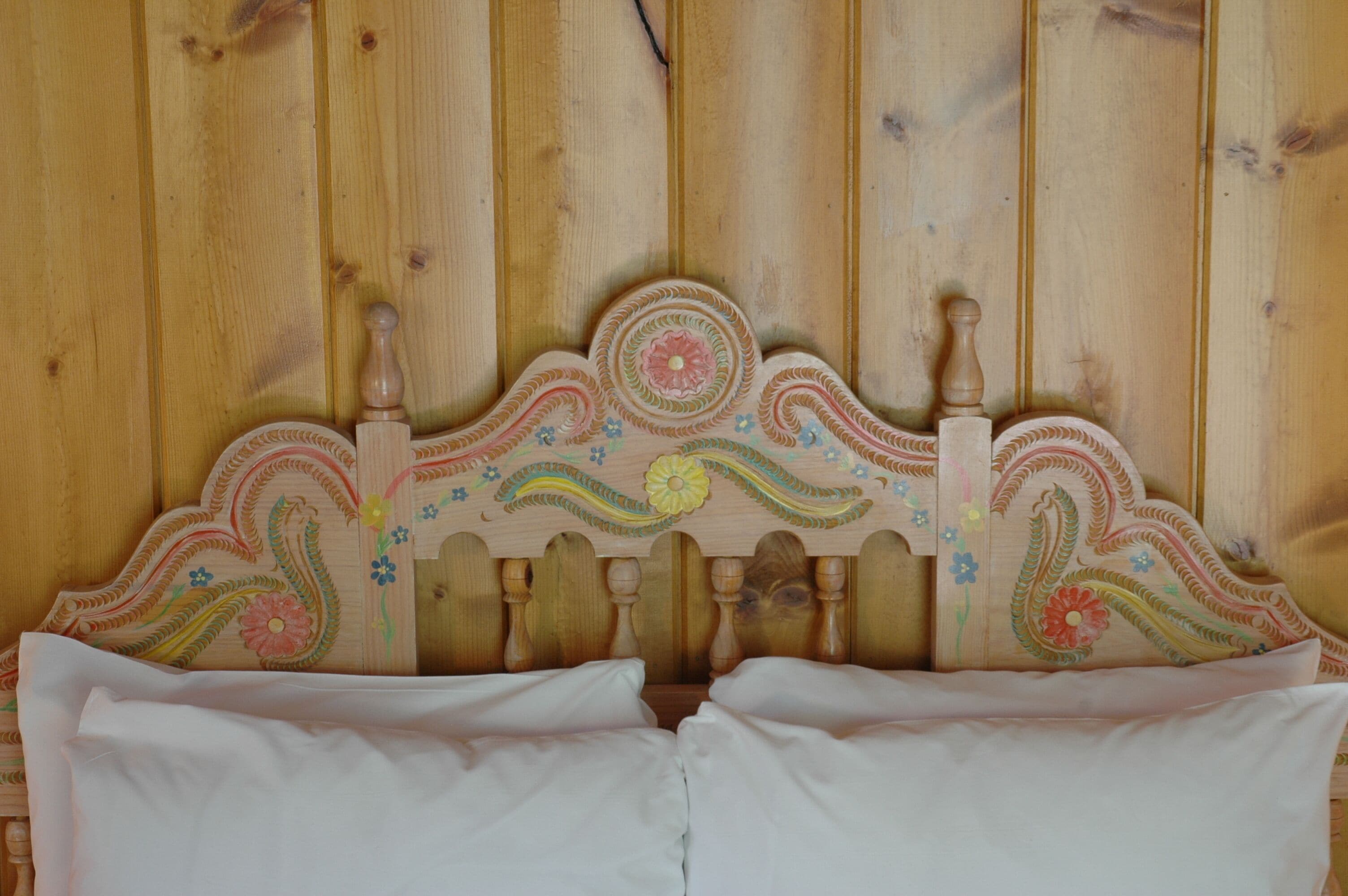 A wooden headboard with floral carvings and a wooden finish.