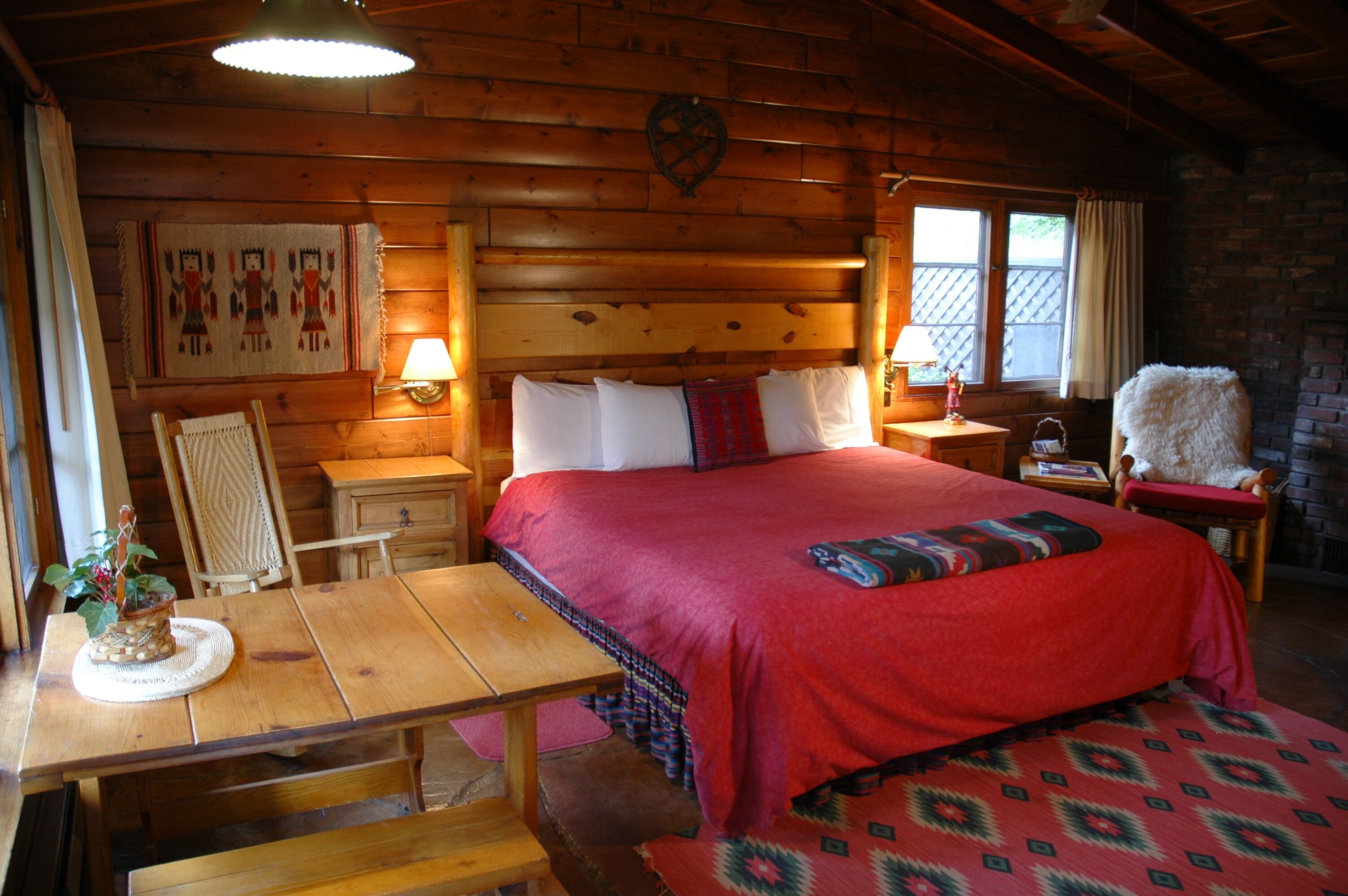 A wooden cabin room with a large bed, a wooden table, and a bench.