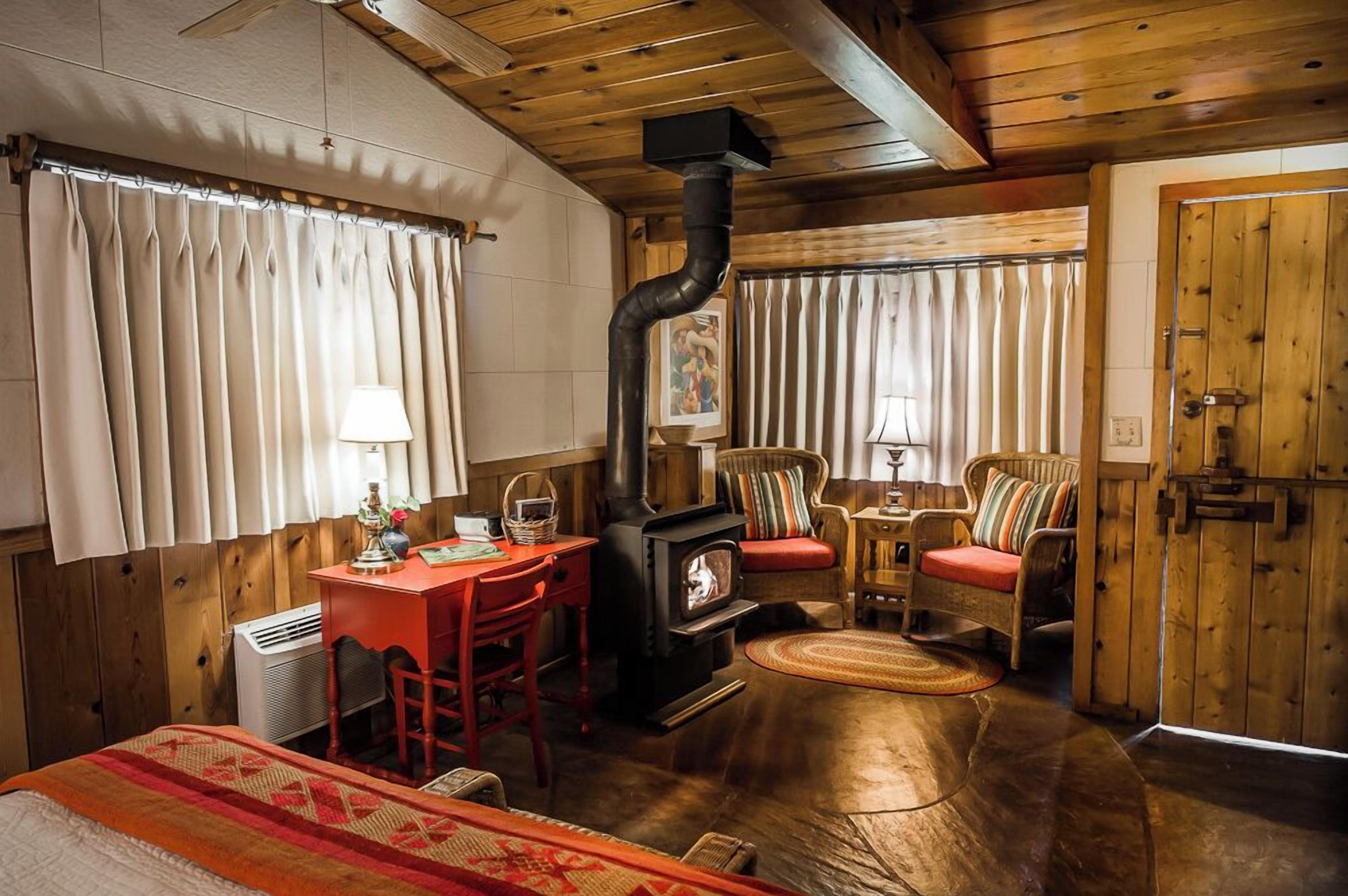 A cozy room with a wooden interior, a fireplace, a desk, and comfortable seating.