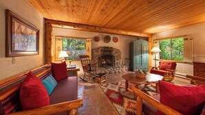 A cozy cabin interior with a stone fireplace, wooden furniture, and a stone floor. - Briar Patch Inn (Sedona)