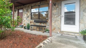 A stone building with a porch, a bench, and a door.