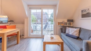 Ein gemütliches Wohnzimmer mit einem Holztisch, einem grauen Sofa und einer großen Schiebeglastür, die zu einer Außenpatio führt.