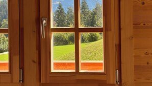 Een houten deur met uitzicht op een berglandschap door een raam.