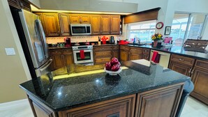 A modern kitchen with wooden cabinets, stainless steel appliances, and a granite countertop.