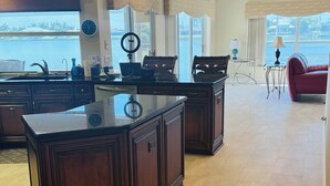 A spacious kitchen with dark wooden cabinetry, a large island, and a view of the water.