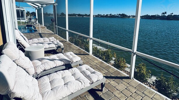 A balcony with lounge chairs and a view of the water.
